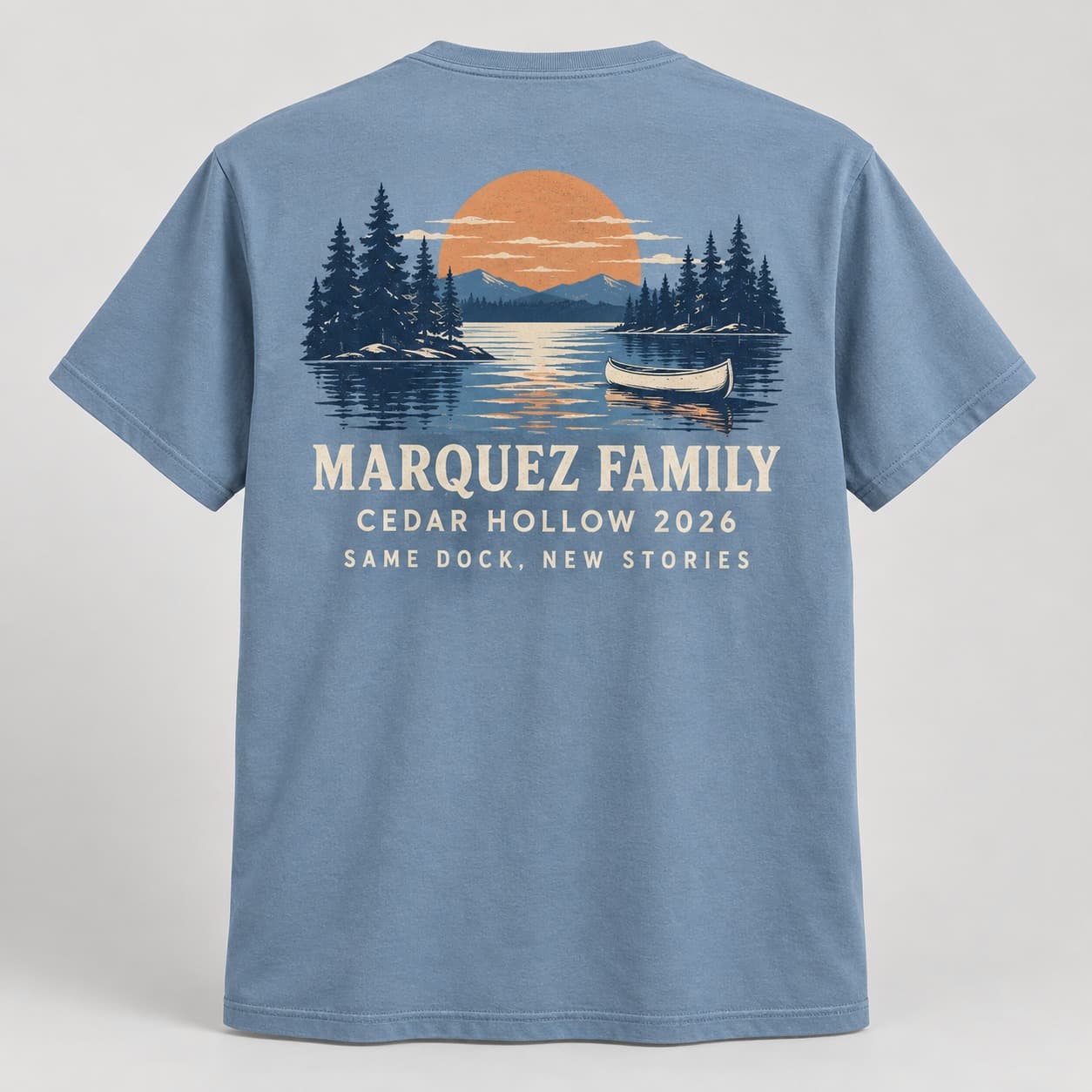 Back of a dusty-blue Marquez Family shirt with a canoe, pine trees, and Cedar Hollow 2026 lettering.