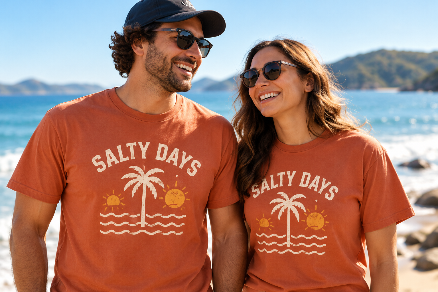 Couple by the coast wearing matching terracotta Salty Days shirts